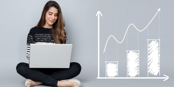 Frau im Schneidersitz am Laptop sitzend sowie ein Balkendiagramm mit Aufwärtstrend und ein Kuchendiagramm